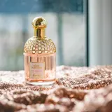 Elegancka butelka perfum Guerlain Aqua Allegoria Pera Granita na błyszczącym materiale. Czy Notino ma oryginalne perfumy? Ten flakon wygląda autentycznie.