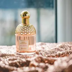 Elegancka butelka perfum Guerlain Aqua Allegoria Pera Granita na błyszczącym materiale. Czy Notino ma oryginalne perfumy? Ten flakon wygląda autentycznie.