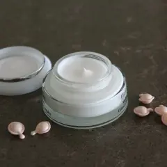 Szukasz odpowiedzi na forum: jaki krem po 50 roku życia? Na zdjęciu krem w słoiczku i kapsułki z serum.