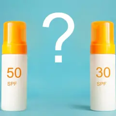 Jaki SPF do twarzy wybrać? Dwa kremy z filtrem SPF 50 i SPF 30 stoją obok siebie, a nad nimi wielki znak zapytania.