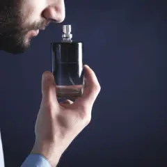 Mężczyzna wącha flakonik, szukając najbardziej trwałych perfum męskich. Elegancki zapach na cały dzień.