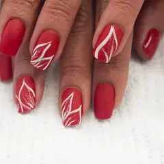 Czerwone paznokcie ze złotym zdobieniem w kształcie liści. Matowe, eleganckie, przyciągające wzrok.