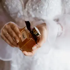 Dłonie trzymają buteleczkę perfum Chloé, idealną do ślubnego rankingu perfum damskich.