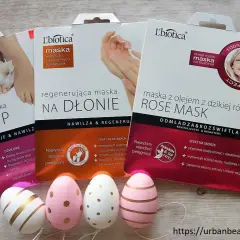 Zestaw masek do stóp, dłoni i twarzy L'biotica z olejkiem z dzikiej róży. Obok wielkanocne pisanki i żonkile.