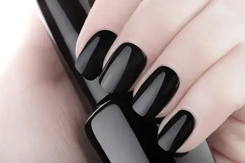 Dłoń z idealnie wykonanymi, błyszczącymi czarnymi paznokciami z frenchem.