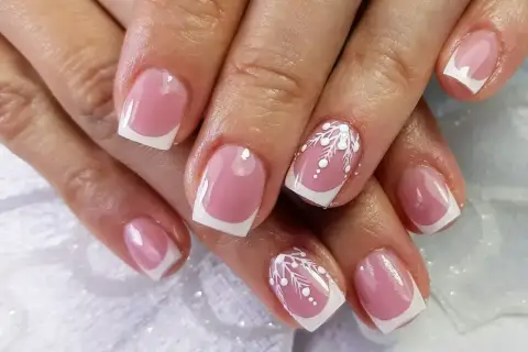 Eleganckie paznokcie konstrukcyjne w stylu francuskim z delikatnym białym zdobieniem przypominającym śnieżynki.