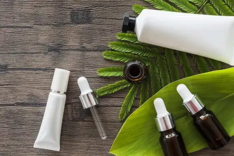 Buteleczki z serum i kremem na drewnianym tle, wśród liści. Dylemat: retinol czy retinal?