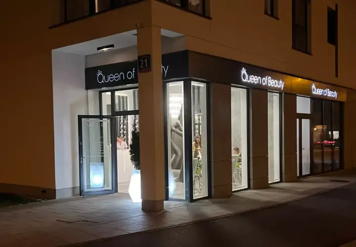 Elegancki salon "Queen of Beauty" nocą. Wnętrze rozświetlone, widać klientki. Czekam na pozytywne queen of beauty opinie!