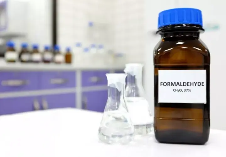 Butelka z etykietą "FORMALDEHYDE CH₂O, 37%" i kolby laboratoryjne. Formaldehyd co to?