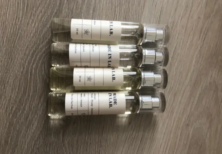Cztery małe flakoniki perfum "MADE IN LAB." na drewnianym tle. Opinie o nich są pozytywne, doceniane za zapachy.