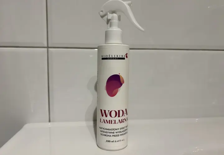 Biała butelka z atomizerem, na której widnieje napis "WODA LAMELARNA". Produkt do włosów.