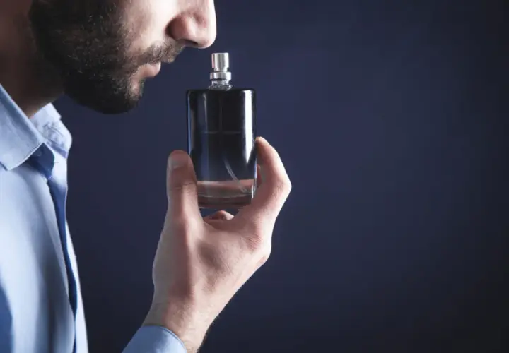 Mężczyzna wącha flakonik, szukając najbardziej trwałych perfum męskich. Elegancki zapach na cały dzień.