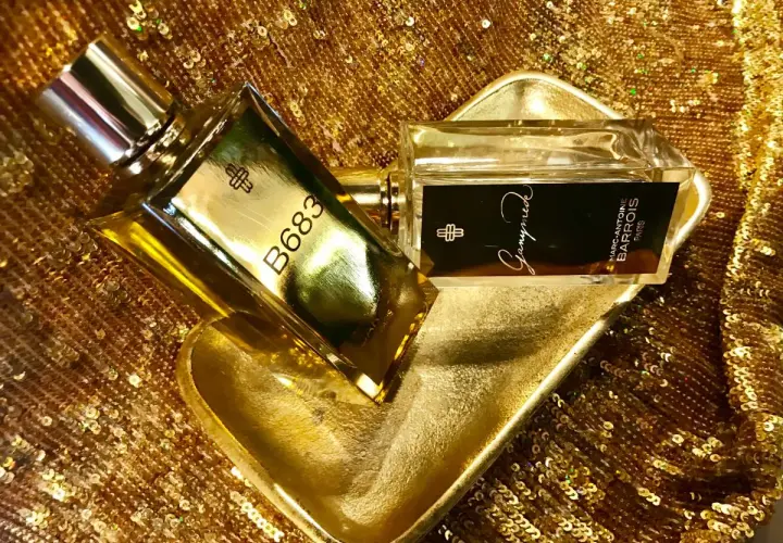 Dwa flakony perfum Marc Antoine Barrois, jeden z napisem B683, drugi z Ganymede, na złotej, cekinowej tkaninie.
