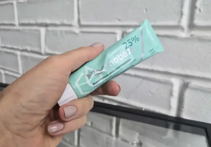 Dłoń trzyma tubkę serum Niacynobaza 25%. Wiele pozytywnych niacynobaza 25% opinii potwierdza jego skuteczność.