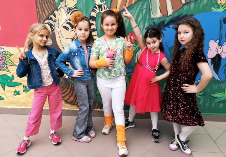 Pięć dziewczynek w kolorowych strojach, gotowych na imprezę w stylu disco.