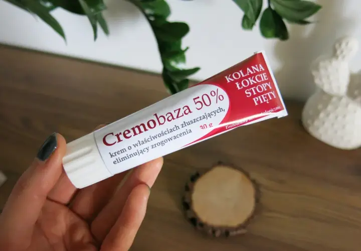 Dłoń trzyma tubkę kremu Cremobaza 50%, który pomaga na zrogowacenia. Brak informacji o skutkach ubocznych.