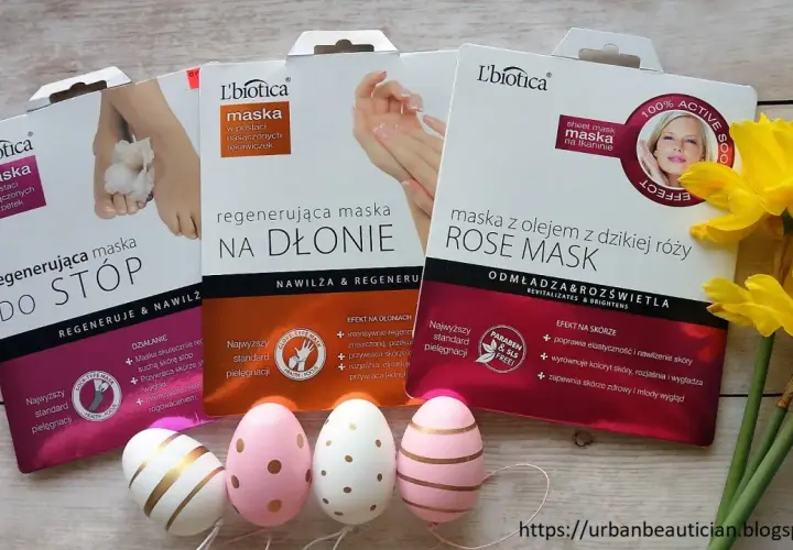 Zestaw masek do stóp, dłoni i twarzy L'biotica z olejkiem z dzikiej róży. Obok wielkanocne pisanki i żonkile.