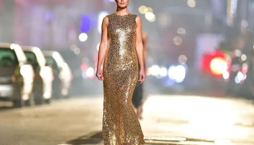 Modelka w złotej sukience z cekinami. Jakie buty do złotej sukienki? Eleganckie szpilki lub sandałki podkreślą stylizację.