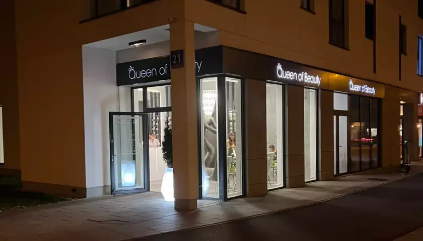 Elegancki salon "Queen of Beauty" nocą. Wnętrze rozświetlone, widać klientki. Czekam na pozytywne queen of beauty opinie!