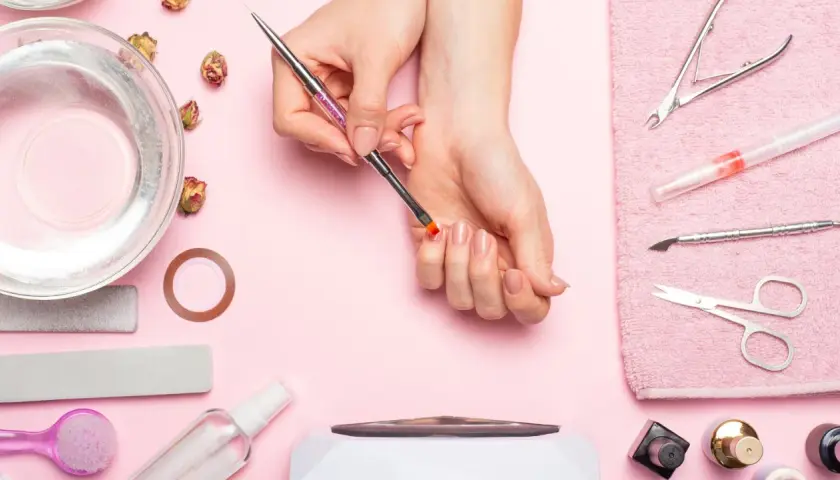 Narzędzia do manicure i dłonie przygotowujące się do zabiegu. Dowiedz się, jak zdjąć tipsy i uzyskać naturalny wygląd paznokci.