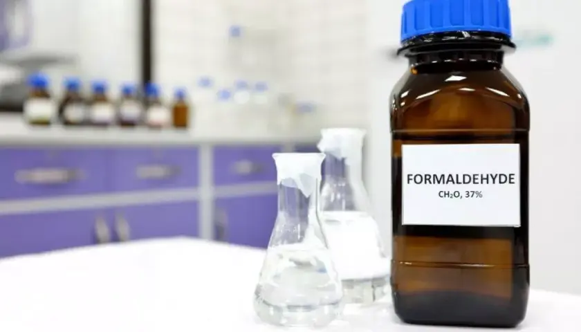 Butelka z etykietą "FORMALDEHYDE CH₂O, 37%" i kolby laboratoryjne. Formaldehyd co to?