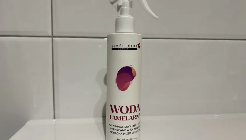 Biała butelka z atomizerem, na której widnieje napis "WODA LAMELARNA". Produkt do włosów.