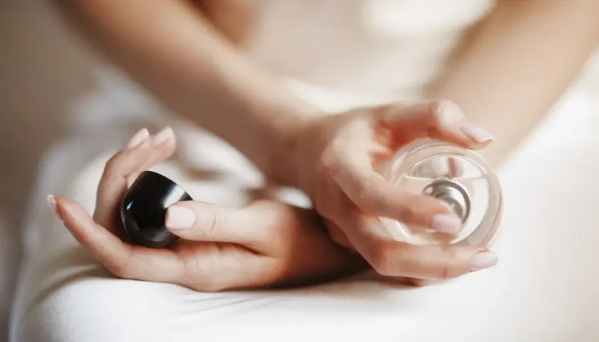 Dłonie kobiety trzymają perfumy. Chcesz wiedzieć, gdzie sprawdzić kod perfum?