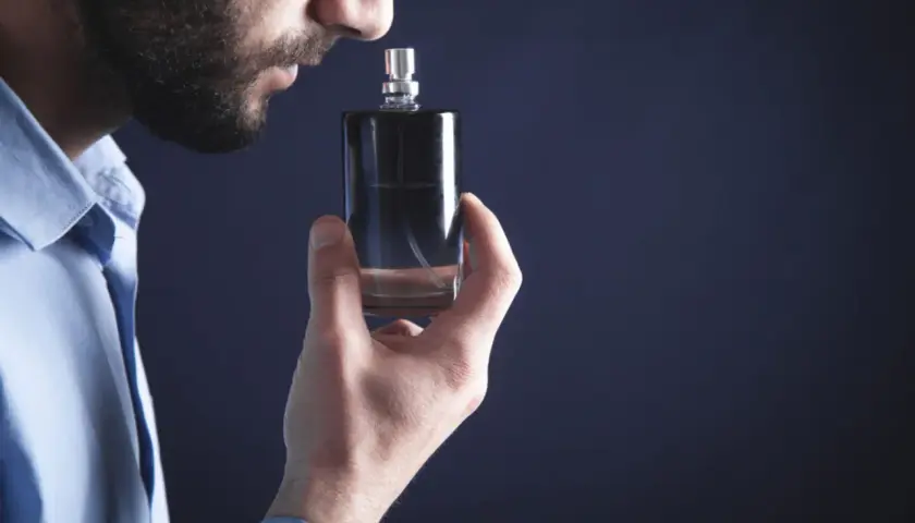 Mężczyzna wącha flakonik, szukając najbardziej trwałych perfum męskich. Elegancki zapach na cały dzień.