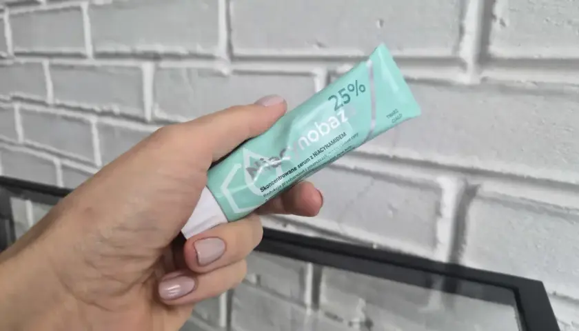 Dłoń trzyma tubkę serum Niacynobaza 25%. Wiele pozytywnych niacynobaza 25% opinii potwierdza jego skuteczność.