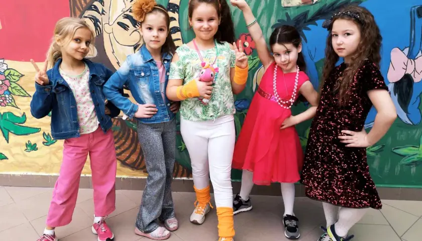 Pięć dziewczynek w kolorowych strojach, gotowych na imprezę w stylu disco.