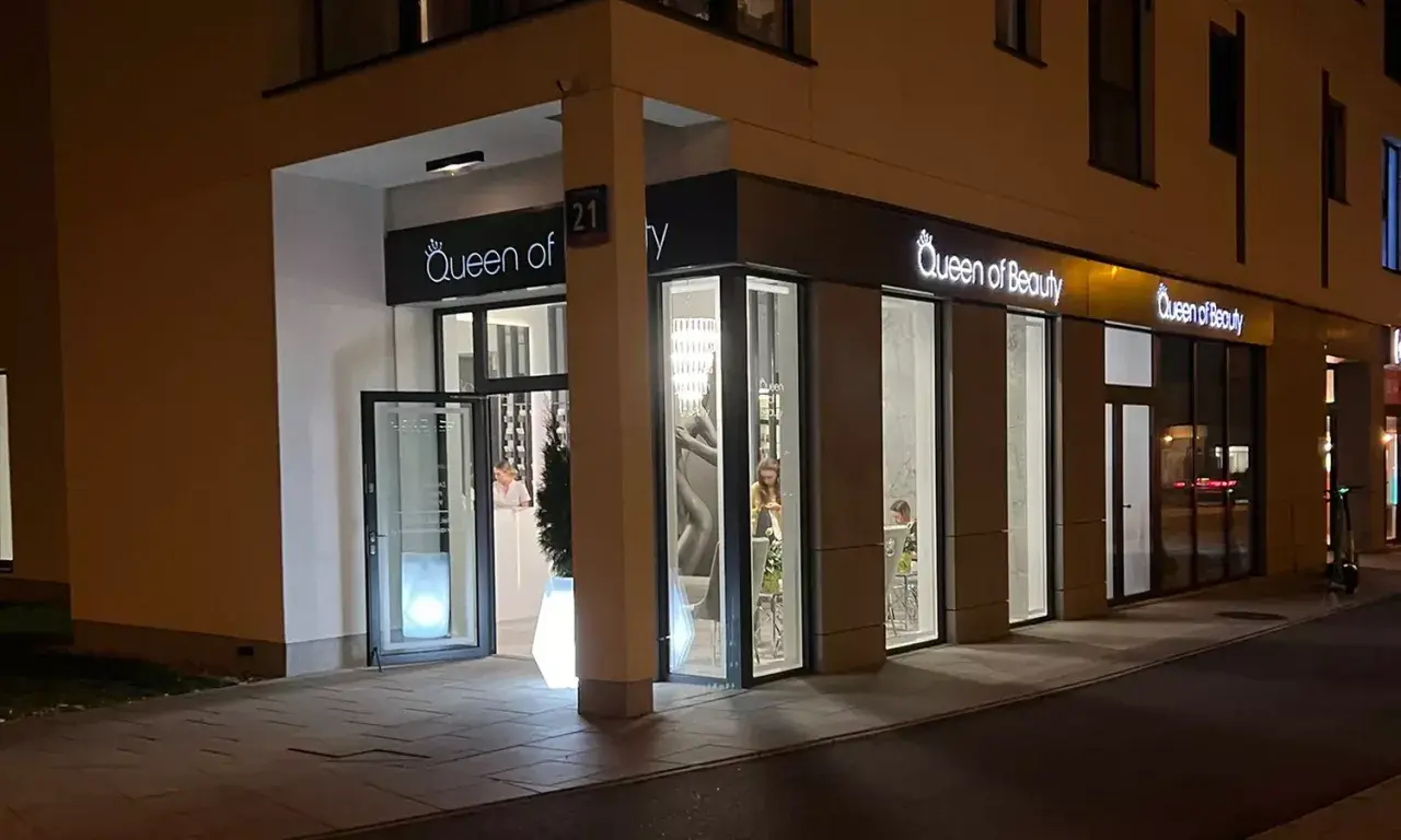 Elegancki salon "Queen of Beauty" nocą. Wnętrze rozświetlone, widać klientki. Czekam na pozytywne queen of beauty opinie!