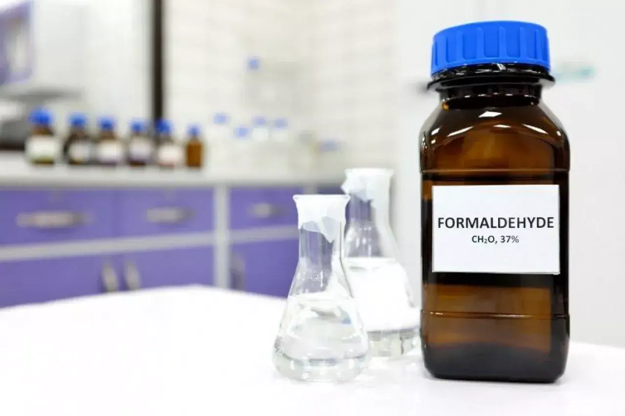 Butelka z etykietą "FORMALDEHYDE CH₂O, 37%" i kolby laboratoryjne. Formaldehyd co to?