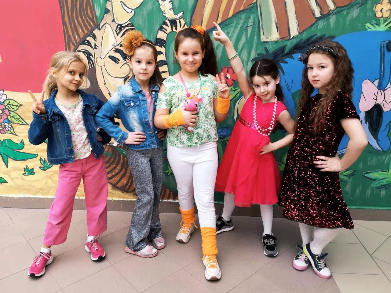 Pięć dziewczynek w kolorowych strojach, gotowych na imprezę w stylu disco.