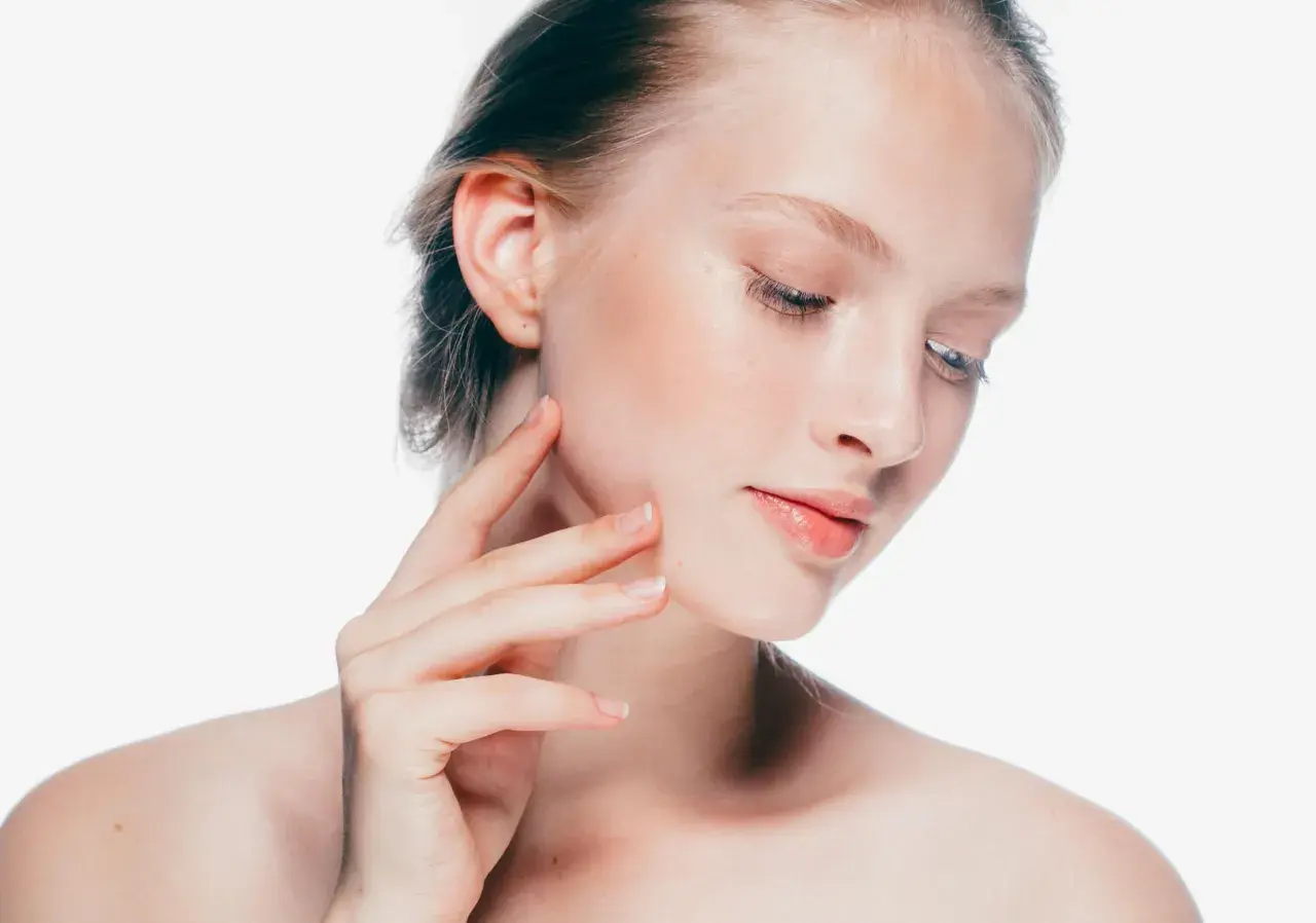 Delikatna gracja młodej kobiety, jej skóra promienieje, a dłoń muśnie policzek.