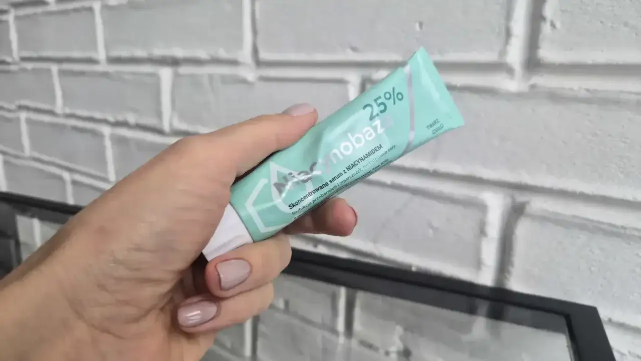 Dłoń trzyma tubkę serum Niacynobaza 25%. Wiele pozytywnych niacynobaza 25% opinii potwierdza jego skuteczność.