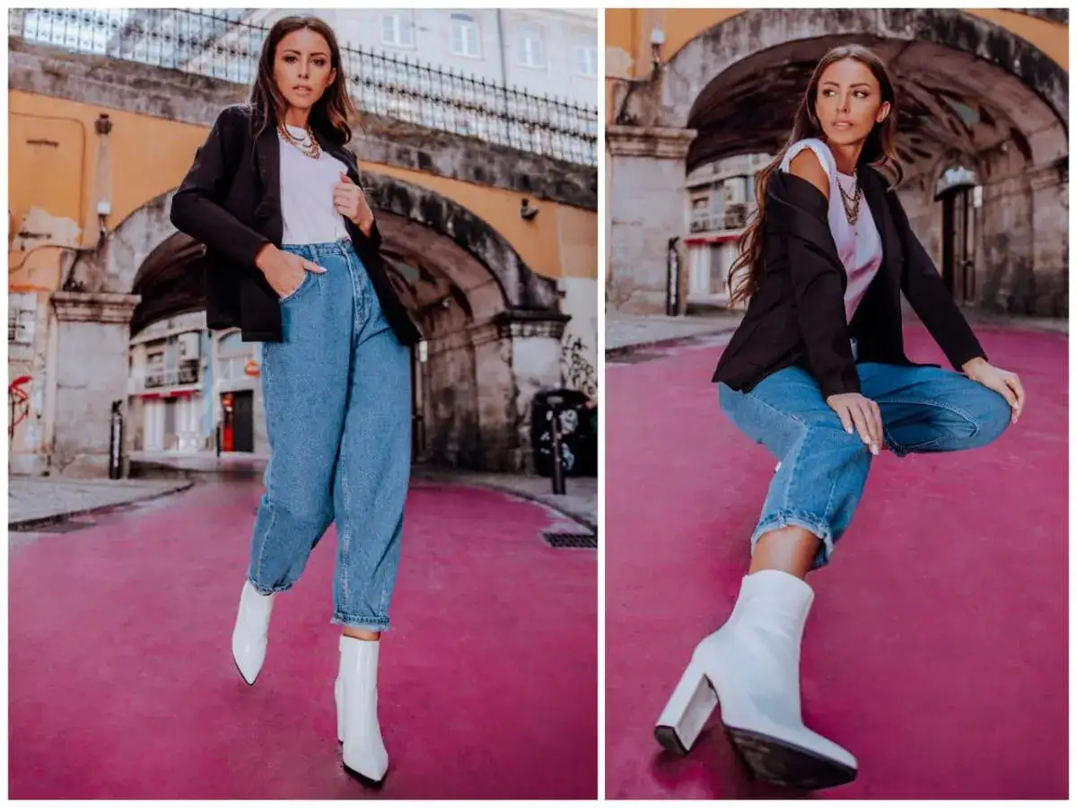 Kobieta w jeansach mom fit i białych kozaczkach na różowym tle. Stylowa stylizacja dla każdej kobiety.