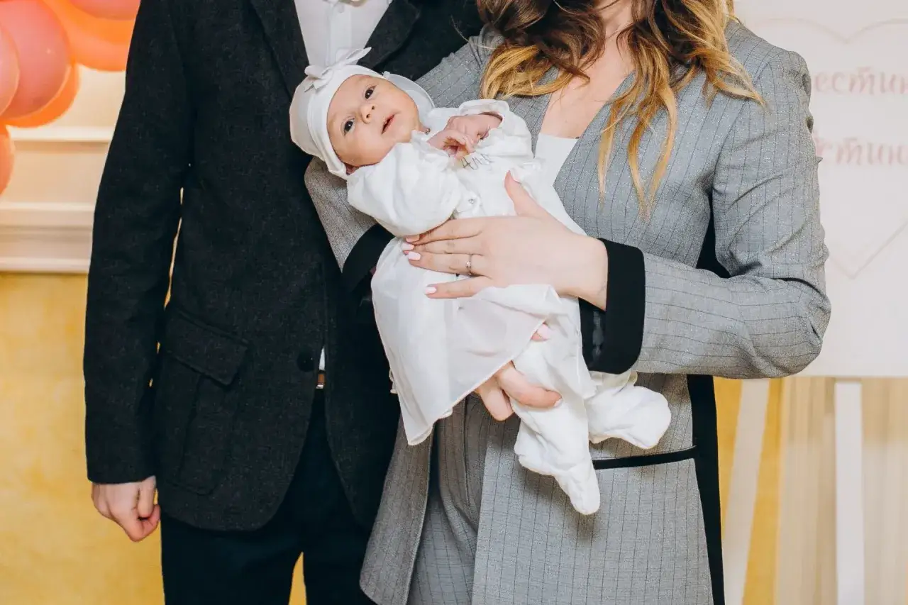 Elegancka stylizacja na chrzciny: mama z dzieckiem w białym ubranku, tata w garniturze.