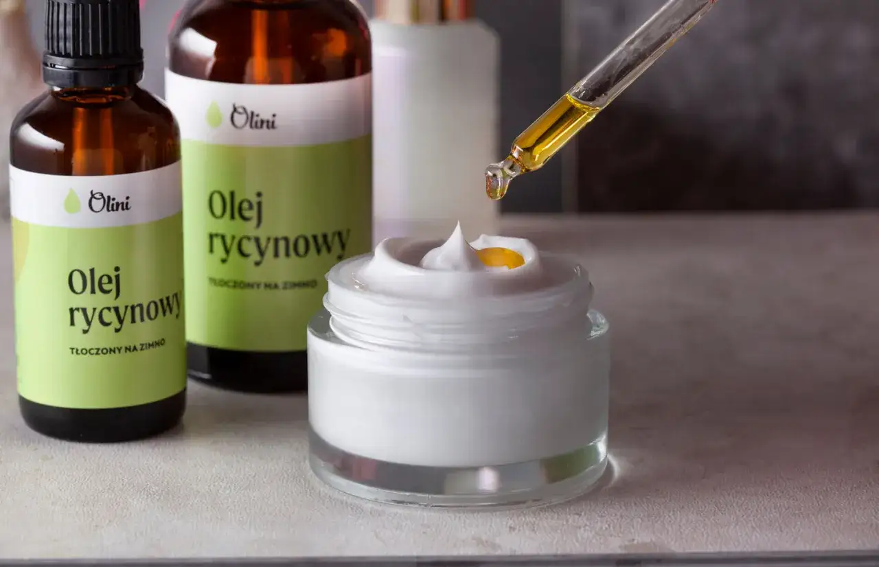 Kropla oleju rycynowego na twarz dodana do kremu. Dwie butelki z zieloną etykietą